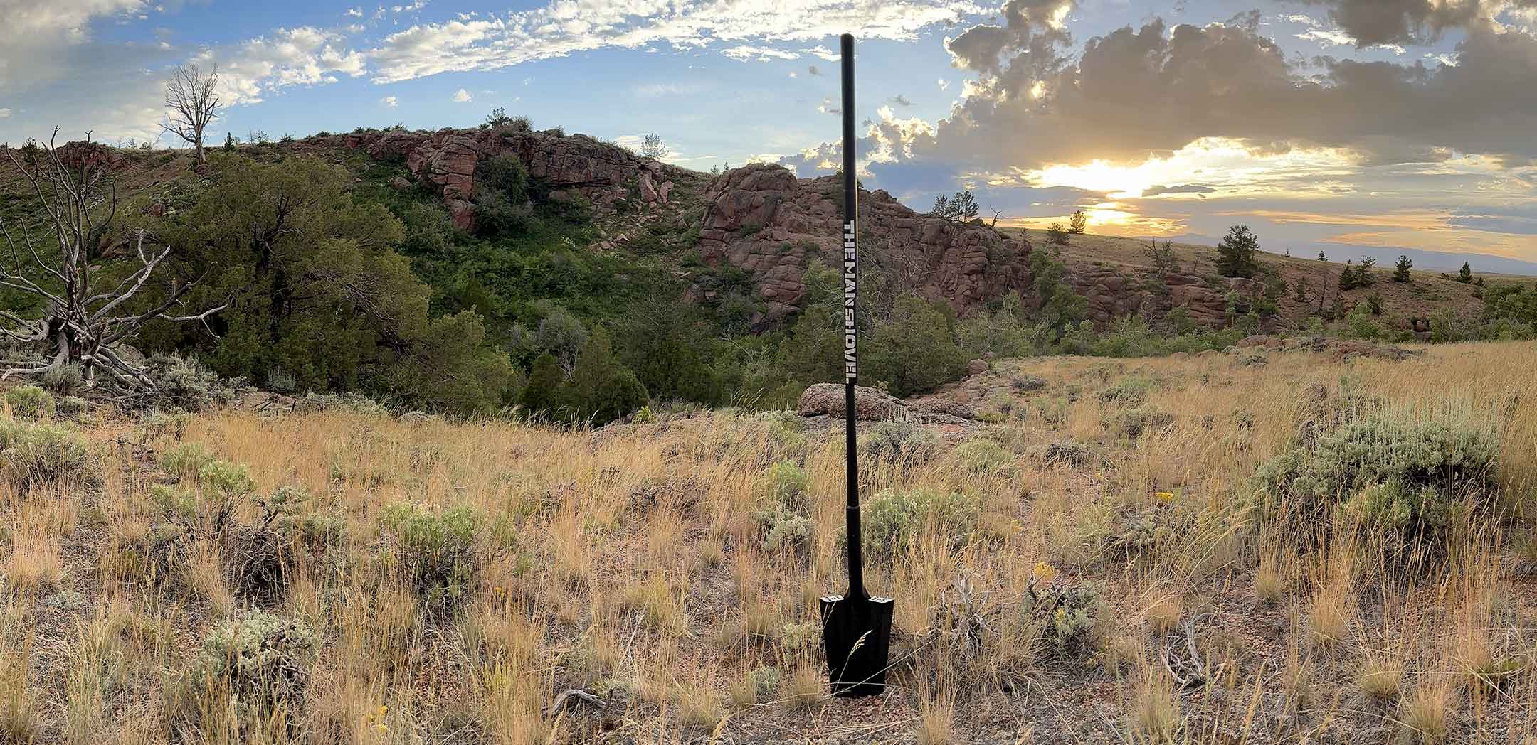 Shovel in a field with a scenic background of mountains and sunset.